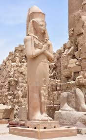 A statue of a person with a large stone structure with Karnak in the background

Description automatically generated with medium confidence